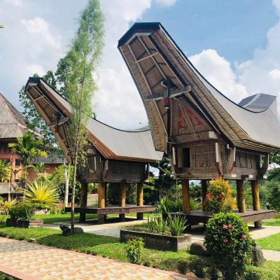 brown wooden house surrounded by green trees under blue sky during daytime
