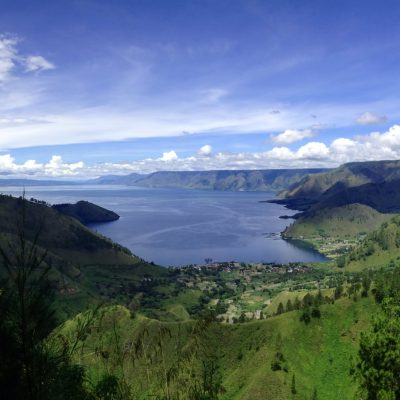 body of water surrounded by green mountains during daytime