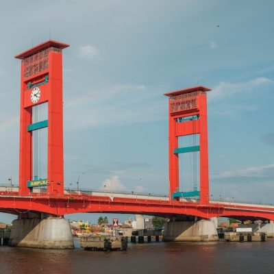 red bridge over river under blue sky during daytime